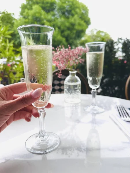 Kafkasyalı bir kızın elinde bir bardak şampanya, dışarıdaki kafede bir masada.. 