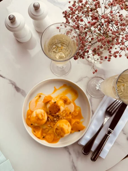 Mango gözlemeleri, yanında dilimlenmiş mango, açık kafedeki masada iki kadeh şampanya..