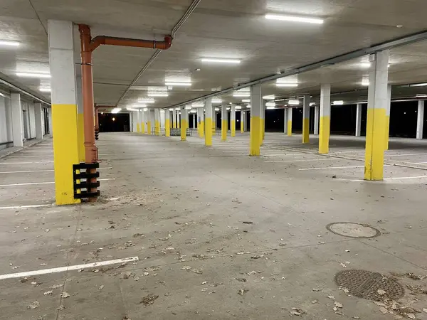 An empty parking lot at night, lit by fluorescent lights. Rows of columns with yellow paint. A solution to the citys parking problem. High quality photo