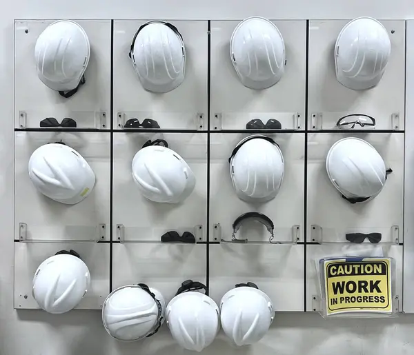 Board for work safety helmets or hard hats and safety glasses for labor protection, workshop industrial background.