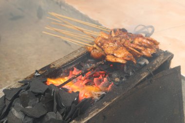 Sate Ayam ya da Chicken satay, ızgarada tavuk satay, nefis görünümlü insanlar tarafından yerleştirilmiş dumanlı, geleneksel java, Madura, Endonezya soslu