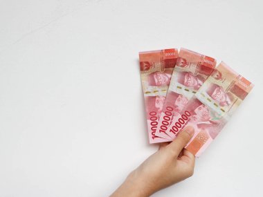 Beyaz arka planda izole edilmiş toplam üç yüz bin rupia banknotuyla el ele tutuşmak. Endonezya Rupisi