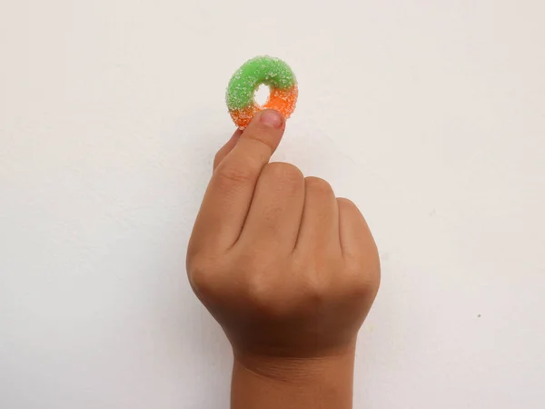 finger holding candy on white background