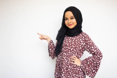 Beyaz arka planda izole edilmiş Asyalı genç bir kadın. İlan için elinle kopyalamak için yer gösterirken gülümsüyor.