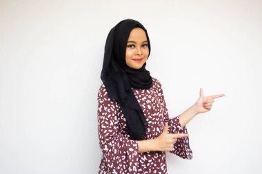 Beyaz arka planda izole edilmiş Asyalı genç bir kadın gülümserken iki eliyle reklam için yeri kopyalayacak.