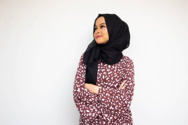 Beyaz arka planda izole edilmiş Asyalı tesettürlü genç kadın kopyalama alanı ararken poz veriyor ve gülümsüyor