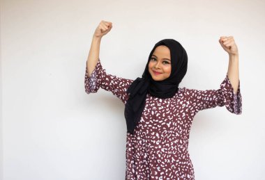 Beyaz arka planda izole edilmiş Asyalı genç kadın zaferi kutluyor ya da ruh veriyor.