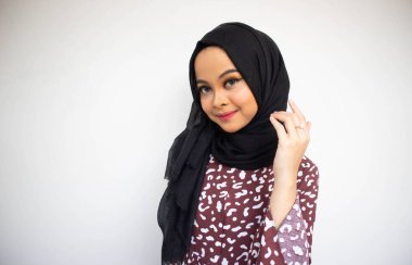 Beyaz arka planda sırıtırken Asyalı tesettürcü kız pozu