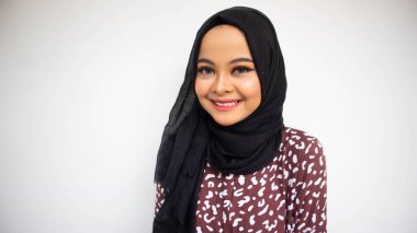 Beyaz arka planda sırıtırken Asyalı tesettürcü kız pozu