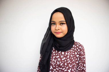 Beyaz arka planda sırıtırken Asyalı tesettürcü kız pozu