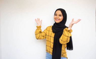 Neşeli Asyalı güzel tesettürcü kız sarı gömlekli, beyaz arka planda soyutlanmış.