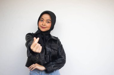 Asyalı güzel tesettürlü kız aşk Kore işaretini parmak ile gösteriyor. Arka planda bulanık, izole beyaz bir zemin var. Endonezyalı Kadınlar