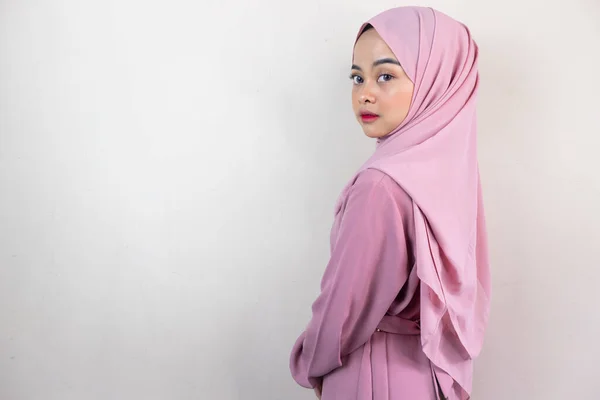 Beautiful Asian woman in pink hijab looks back isolated over grey background