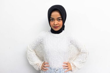 Beautiful young Asian Muslim in casual shirt, put hands on waist to show feeling proud isolated over grey background