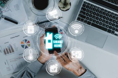 Akıllı ev otomasyon kontrol sistemi, akıllı ev kontrol simgesi olan akıllı telefon kullanan insan eli VR ekranda, inovasyon teknolojisi internet ağı konsepti.