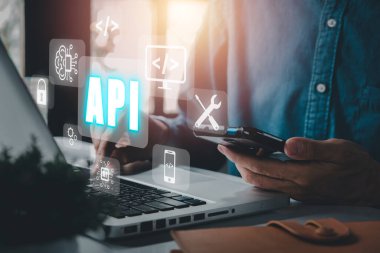 API - Uygulama Programlama Arayüzü, Ofis masasında VR ekran API simgesi olan dizüstü bilgisayar kullanan kadın, Yazılım geliştirme aracı, modern teknoloji, internet ve ağ konsepti.