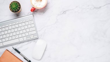 Top view, White marble Office desk with keyboard computer, cup of coffee, pen, mouse and notebook, copy space, Mock up..	