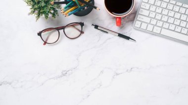 Üst manzara, klavye bilgisayarlı beyaz ofis masası, bir fincan kahve, kalem ve gözlük, fotokopi alanı,...