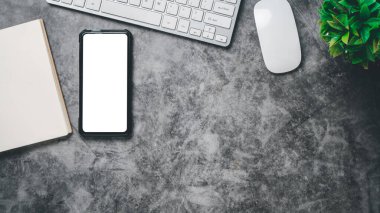 Top view, Dark Office desk with keyboard computer, Blank screen smart phone, mouse and notebook, copy space, Mock up...	