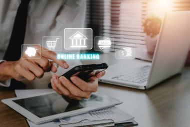 Genç adam internet bankacılığı simgesiyle ofis masasında akıllı telefon kullanıyor. Teknoloji E-Ticaret Ticareti. Çevrimiçi ödeme dijital ve ağ bağlantısı üzerinden alışveriş. 