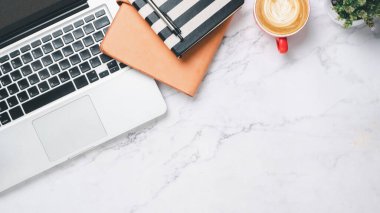 Üst görünüm, dizüstü bilgisayarlı beyaz ofis masası, bir fincan kahve, kalem ve defter, kopyalama alanı,.