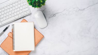 Klavye bilgisayarı, faresi, kalemi ve defteri olan beyaz ofis masası, kopyalama alanı olan üst görünüm,.