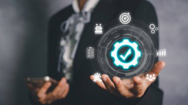 QA (güvence), QC (kontrol) ve iyileştirme ile kalite yönetimi, siyah arkaplanda VR ekran kalitesi ikonu ile akıllı telefon ve el ele tutuşan iş kadını.