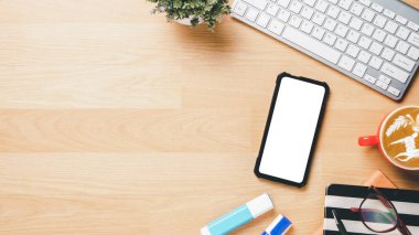 Klavye bilgisayarlı ofis masası, boş ekran akıllı telefon, gözlük, kalem, defter ve kahve, fotokopi alanı olan üst görünüm,.