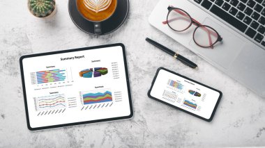 Tablet and smartphone with charts and reports on office desk workplace. Top view flat lay