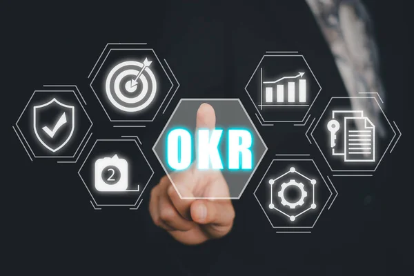 OKR, Objectives and Key Results concept, Business person hand touching Objectives and Key Results icon on virtual screen, Methods for project management.