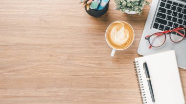 Wooden desk workplace with laptop computer, notebook, eyeglass, pen and cup of coffee, Top view flat lay with copy space.