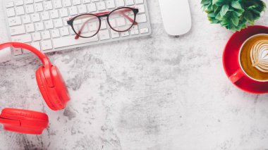 Office desk workplace with keyboard computer, mouse, eyeglass, headphone and cup of coffee, Top view flat lay with copy space.