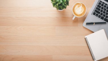 Wooden desk workplace with laptop computer, notebook, pen and cup of coffee, Top view flat lay with copy space.