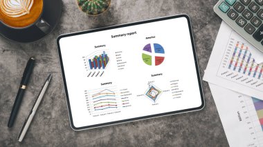 Tablet with charts and reports on office desk workplace. Top view flat lay.	