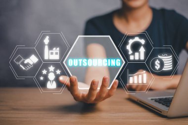 Outsourcing Global Recruitment Business and internet concept, Business person hand holding outsourcing icon on virtual screen with blue bokeh background. clipart