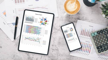 Tablet ve akıllı telefon, çalışma masasında dosyalar ve raporlar. Üst görünüm düzlüğü