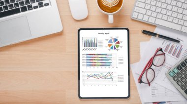 Tablet with charts and reports on office desk workplace. Top view flat lay.	