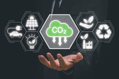 Reduce CO2 emission concept, Person hand holding CO2 icon on virtual screen, Sustainable development and green business based on renewable energy, electric transport. clipart