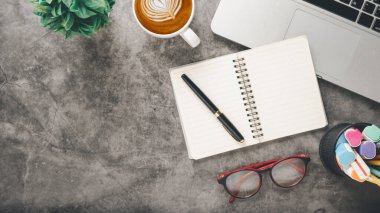 Dizüstü bilgisayarı, kalemi, defteri, gözlüğü ve kahvesi olan ofis masası işyeri..