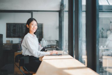 Ofiste dizüstü bilgisayarda çalışan genç bir iş kadınının portresi elinde kahve fincanı tutan bir kadın..