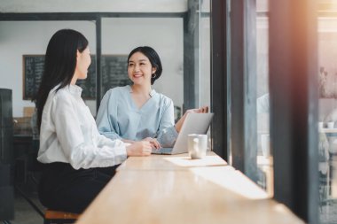 Gülümseyen genç iş kadını iş ortağını iş yerinde dinliyor..