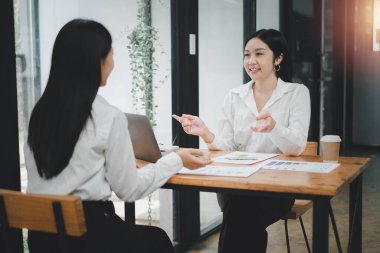 Ofisteki masada oturmuş belgeleri analiz eden iki kadın. Ofisteki kadın yöneticiler bazı evrak işlerini tartışıyorlar..