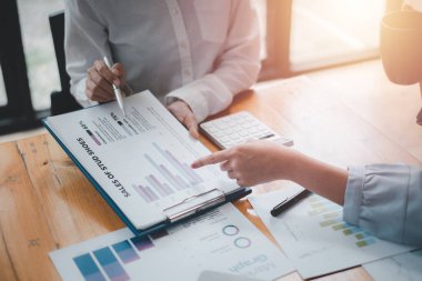 Bir grup işadamı, işletme işletme giderleri ve şirketin mali durumuyla ilgili çalışma verilerinin özet grafik raporlarını analiz ediyor..