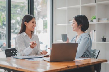 Ofisteki masada oturmuş belgeleri analiz eden iki kadın. Ofisteki kadın yöneticiler bazı evrak işlerini tartışıyorlar..
