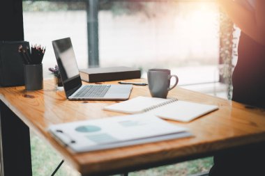 Office desk workplace with laptop and business paper on wooden table with copy space.	