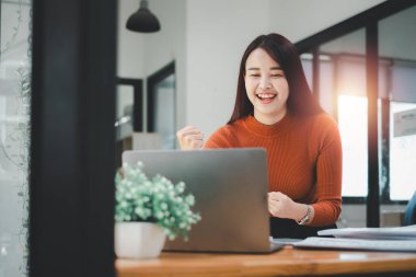 İş kadını ofisteki dizüstü bilgisayarla başarılı olduğu için mutlu ve neşeli..