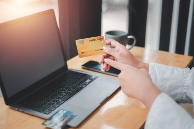 Kredi kartı tutan kadın ve boş ekranlı dizüstü bilgisayar kullanan ev kadını. Çevrimiçi alışveriş, e-ticaret, internet bankacılığı, harcama.