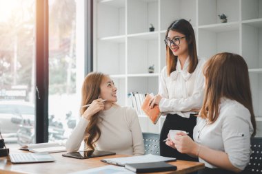 Gülümseyen çeşitli çalışanlar gülerek iş birliği yapıyor ofis ekibinin toplantısında bilgisayar üzerinde beyin fırtınası yapıyorlar. Mutlu çok ırklı iş adamları dizüstü bilgisayarda birlikte çalışıyorlar iş fikirlerini grup halinde tartışıyorlar..