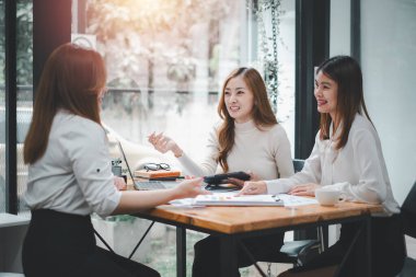 Three women analyzing documents while sitting on a table in office. Woman executives at work in office discussing some paperwork.	