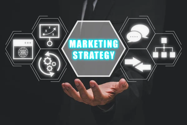 Marketing strategy concept, Businessman hand holding marketing strategy icon on virtual screen.